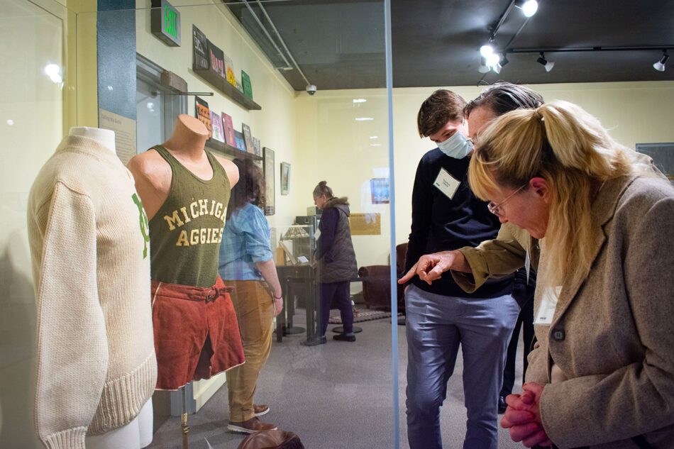 Guests observing a display of vintage MSU clothing in the exhibition hall.