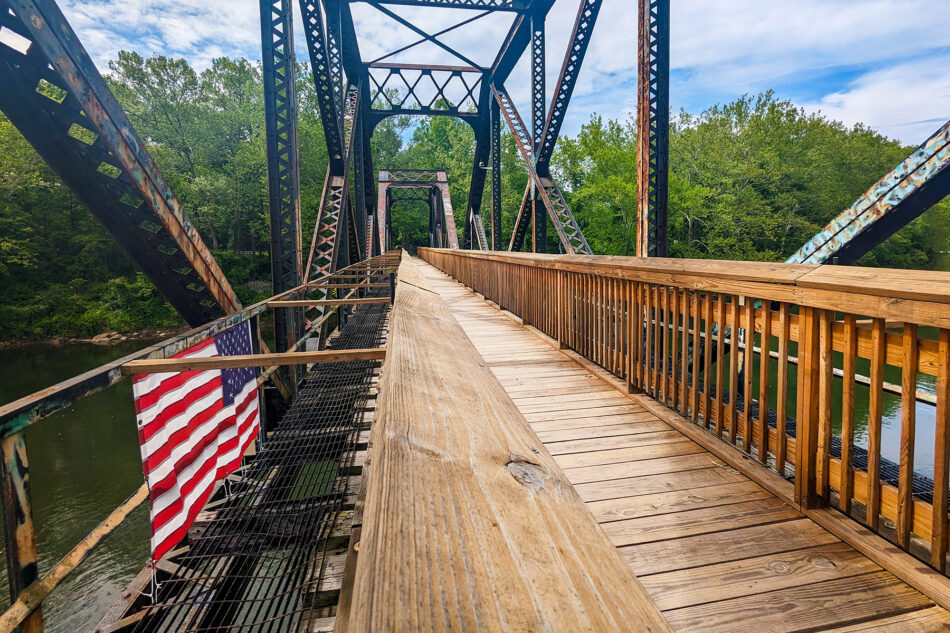 An American flag hanging on the side of an abandoned bridge.