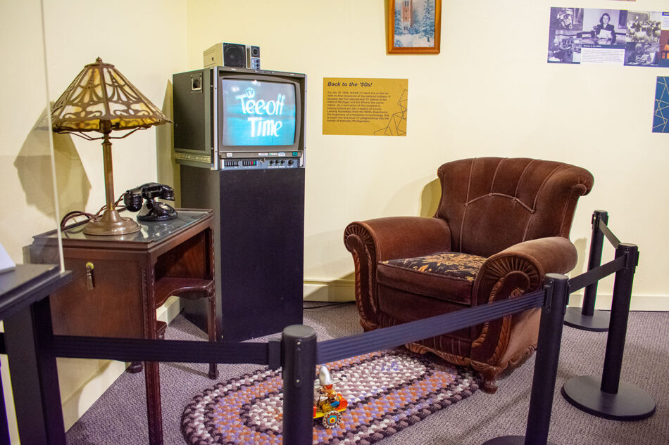 A display replicating a living room with archived WKAR video on the television screen.
