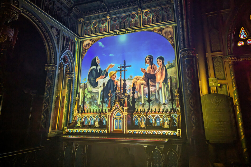 Illuminated station at Notre-Dame Basilica, displaying a glowing mural of religious figures with intricate detail, set against a dark architectural backdrop.